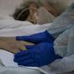Dr Moyra Lopez holds the hand of a terminally ill patient at the Barros Luco hospital ward in Santiago where loved ones are able to see dying patients even if they have contracted the coronavirus