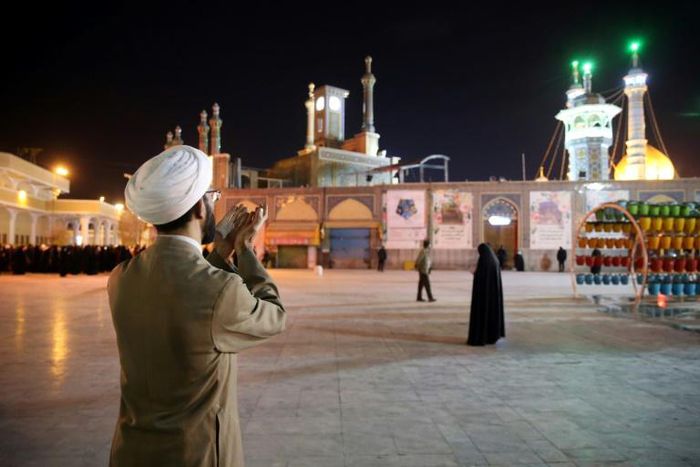 A cleric prays outside the Fatima Masumeh shrine in Iran's holy city of Qom on March 16, 2020, the day it was closed due to the coronavirus