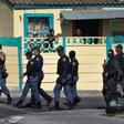South African police patrol the street during clashes with residents (not visible) of Tafelsig, an impoverished suburb in Mitchells Plain, near Cape Town, on April 14, 2020, after some people in the community did not receive food parcels