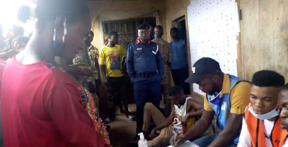 NSCDC official standing close to a young man arrested with a fake PVC (TheCable)