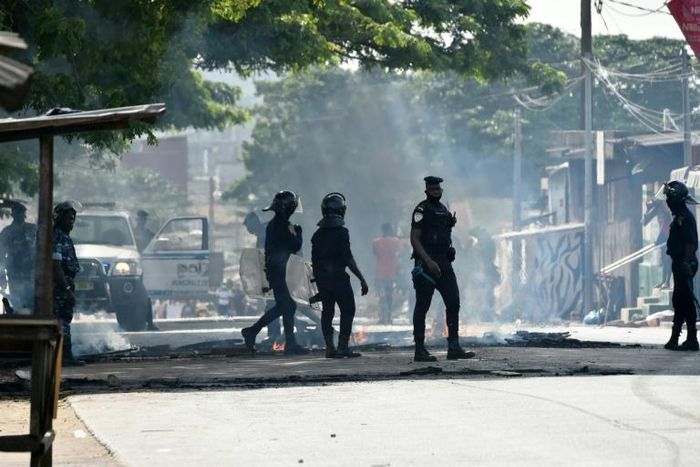 Police clear debris that was placed in the road by young demonstrators during protests against President Alassane Ouattara's run for a third term, in the Yopougon neighbourhood of Abidjan on August 13, 2020