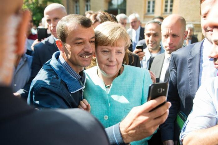 An asylum seeker takes a selfie with German Chancellor Angela Merkel, in Berlin on September 10, 2015 at the beginning of Europe's migrant crisis