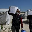 Volunteers deliver aid at a camp for displaced Syrians near the town of Deir al-Ballut, by the border with Turkey, in Syria's Afrin region in the northwest of the rebel-held side of the Aleppo province on April 14, 2020 during the coronavirus pandemic.
