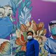 A man wearing a face mask walks past a mural at Leishenshan Hospital in Wuhan in April