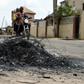 A motorcycle taxi in the district of Ojodu drives past the remains of a fire set to ward off gangs of robbers
