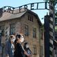 As the site reopens following Coronavirus lockdown, visitors to Auschwitz contemplate the  entrance gate with its inscription "Work sets you free"