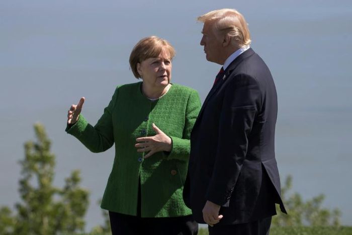 German Chancellor Angela Merkel confers with US President Donald Trump following a family photo session during the G7 Summit in La Malbaie, Canada in 2018