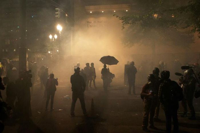 Protesters stand amid tear gas near the federal courthouse in  Portland, Oregon during a rally against police brutality late on July 24, 2020