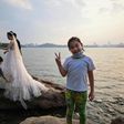 A girl gestures while a couple poses for a wedding photographer next to East Lake in Wuhan
