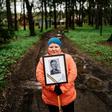 A woman carries a portrait of her grandfather near a monument in a small village outside Moscow dedicated to those who fought in World War II