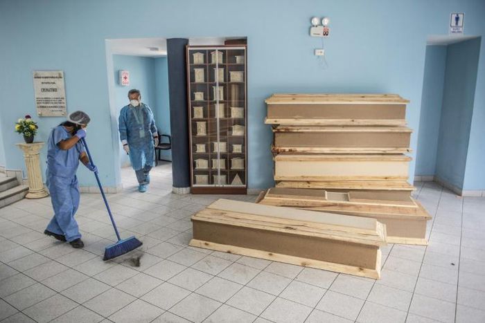 A worker sweeps the floor next to coffins for Covid-19 victims at El Angel cemetery, in Lima, Peru
