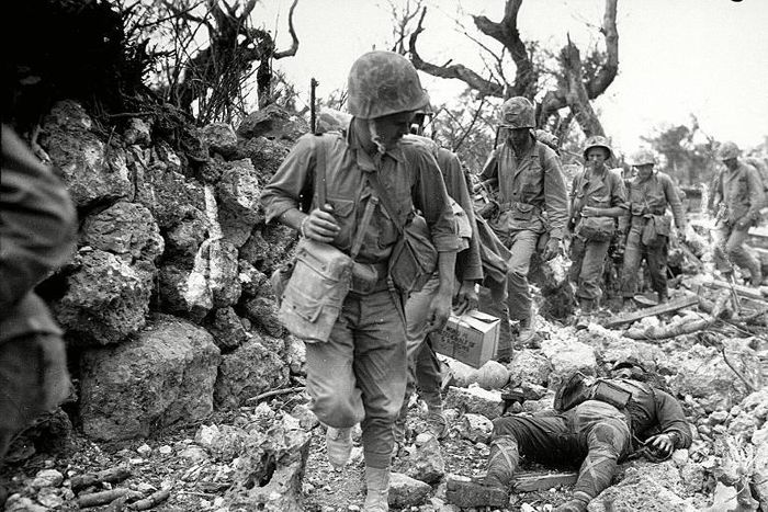 An April 1945 file photo from The National Archives shows US Marines passing through a small village in Okinawa, Japan, where Japanese soldiers lie dead
