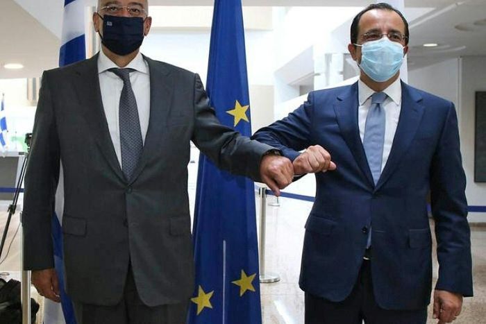 Cypriot Foreign Minister Nicos Christodoulides (R) greets with an elbow bump his Greek counterpart Nikos Dendias in Nicosia