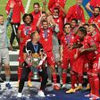 Bayern Munich players and coach Hansi Flick celebrate with the trophy after beating PSG in Sunday's Champions League final in Lisbon