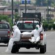People wearing protective suits accompany a coffin on a truck near Los Ceibos hospital in Guayaquil, Ecuador on April 8, 2020