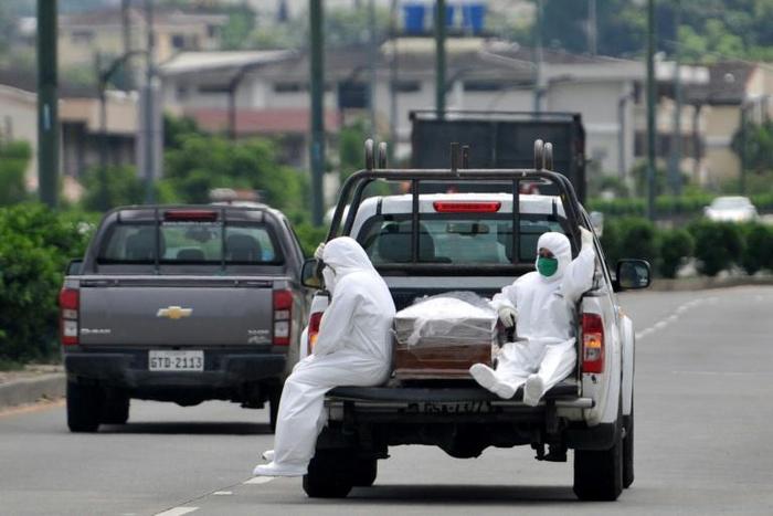 People wearing protective suits accompany a coffin on a truck near Los Ceibos hospital in Guayaquil, Ecuador on April 8, 2020