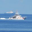 A Philippine coastguard ship BRP Langgam sails past a Chinese coastguard ship (background) near the Scarborough shoal in 2019