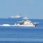 A Philippine coastguard ship BRP Langgam sails past a Chinese coastguard ship (background) near the Scarborough shoal in 2019