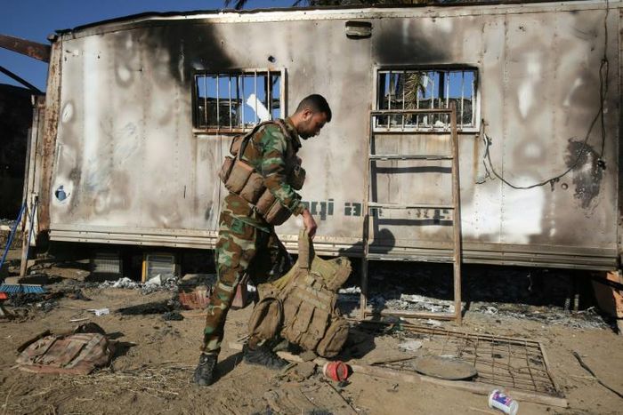 An Iraqi fighter with the Hashed al-Shaabi force inspects the site of the Islamic State group attack in Mukaishefah, about 180 km (110 miles) north of Baghdad, in May 2020