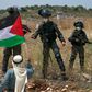 A Palestinian man facing Israeli forces waves a national flag during a protest against Israel's plan to annex parts of the occupied West Bank, near the town of Tulkarm on June 5
