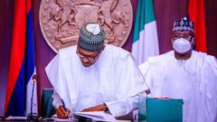 President Muhammadu Buhari signs into law the revised N10.8trn 2020 Budget as President of the Senate, Ahmad Lawan watches on. [Twitter/@Buharisallau1]