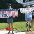 Supporters of Donald Trump and Joe Biden wave competing signs as the president's convoy arrives at a golf course in Sterling, Virginia, on August 23, 2020