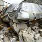 A villager inspects a damaged car among the debris of houses after a flash flood hit Charikar