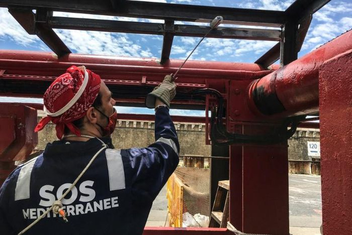A crew member of French NGO SOS Mediterranee rescue boat Ocean Viking paints parts of the boat moored in the port of Marseille, on the eve of a scheduled departure for a migrants search and rescue mission off the coast of Libya