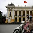 Women wearing face masks ride past the Opera House in Hanoi on April 23, 2020, as Vietnam eased its nationwide social isolation effort to prevent the spread of the COVID-19 novel coronavirus. Vietnam eased social distancing measures on April 23, with e...