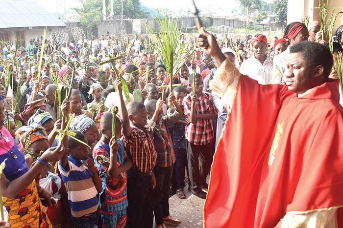 Rev. Fr. Henry Kwasu (right), blessing Catholic faithful and their palms, during the Palm Sunday at the Sacred Heart Catholic Church, Gwagwalada in Abuja… yesterday. PHOTO: NAN