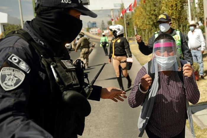 A policeman blocks Celia Capira as she tries to approach Peru's President Martin Vizcarra to plead for help in saving her husband's life as he struggles with coronavirus