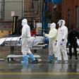 Medical personnel move a deceased patient to a refrigerated truck serving as a makeshift morgue in Brooklyn