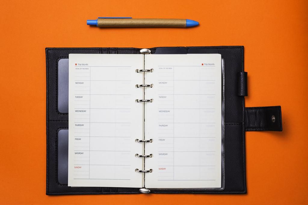 Directly Above Shot Of Open Diary And Book Over Orange Background