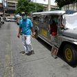 A resident walks past jeepneys serving as temporary homes parked along a road in Manila