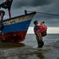 Acehnesse fishermen help carry a Rohingya child ashore after locals defied authorities who didn't want the asylum seekers to land