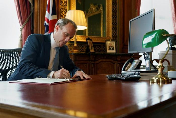 A handout image released by 10 Downing Street, shows Britain's Foreign Secretary Dominic Raab signing a letter to fellow MPs, in the Foreign & Commonwealth Office in central London on July 6, 2020, following the launch of new Human Rights Sanctions