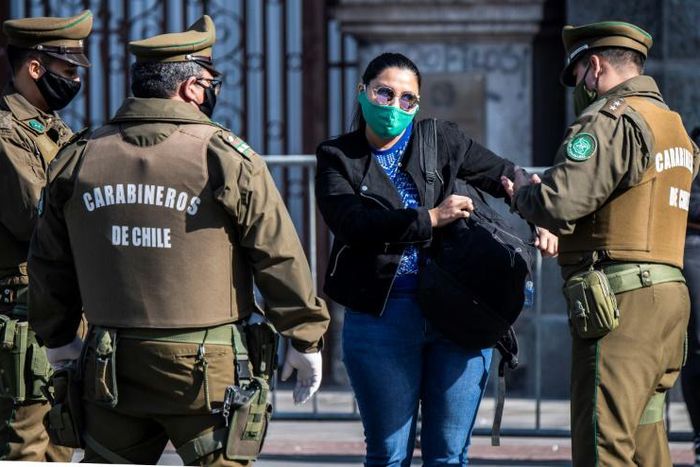 Chilean security forces check a woman's documents as they enforce a total quarantine to prevent the spread of the coronavirus in Santiago, on June 10, 2020