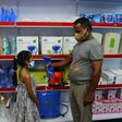 A storekeeper shows to a child a fan-sprinkler used for spraying disinfectant, at a shop selling products against the spread of Covid-19 in Vallabh Vidyanagar, 65km from Ahmedabad, India