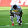 Moenchengladbach's French forward Marcus Thuram takes a knee