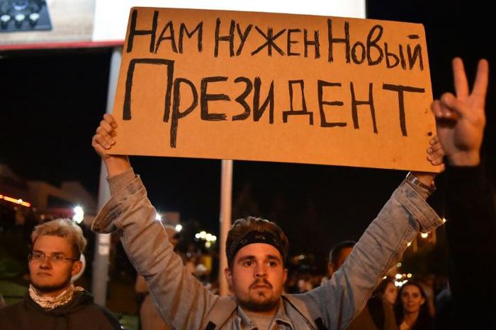 A man holds a poster reading "We need a new president" during a protest rally against police violence