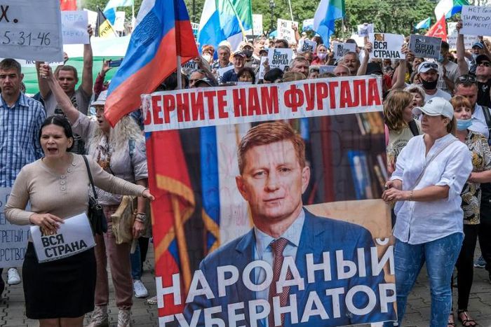 Protestors in the Russian Far East city of Khabarovsk  carry a banner reading "Return Furgal for us", during an unauthorised rally Saturday in support of Sergei Furgal