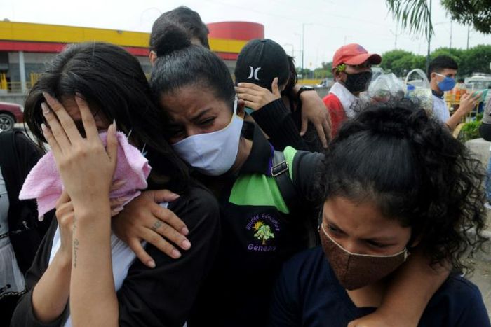 Relatives of a coronavirus victim who died at the start of the pandemic in Ecuador weep as they wait for the recently identified body to be returned to them