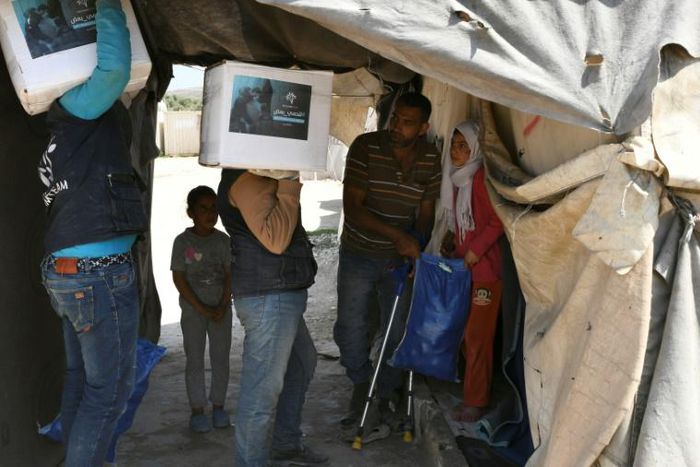 Volunteers deliver aid at a camp for displaced Syrians near the town of Deir al-Ballut in Aleppo province, by the border with Turkey, April 14, 2020 during the coronavirus pandemic