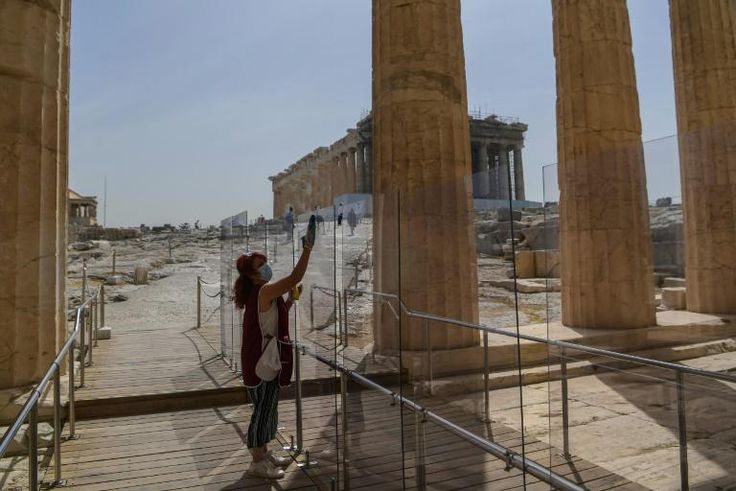 A worker (pictured May 18, 2020) wearing a protective mask cleans a divider made of plexiglass at the entrance of the Acropolis in Athens amid the pandemic of the novel coronavirus