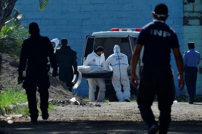 Forensic experts take away a corpse from the women's prison in Tamara, Honduras following the murder of six inmates