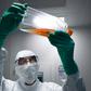 A lab technician in Personal Protective Equipment (PPE) looks at a reagent bottle before performing vaccine tests at French pharmaceutical giant Sanofi's lab in Val de Reuil
