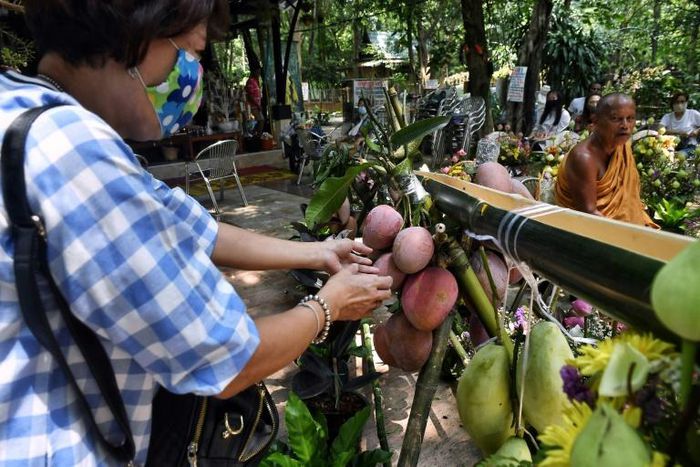 At a temple north of Bangkok worshippers poured water down a bamboo tube to a waiting monk, to maintain  social distancing