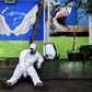 An Indonesian health agency official rests at the entrance to a public toilet as other colleagues conduct COVID-19 testing in Bandung, West Java