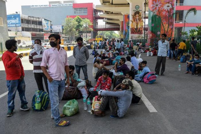Migrant workers and their families wait for transport back to their home towns