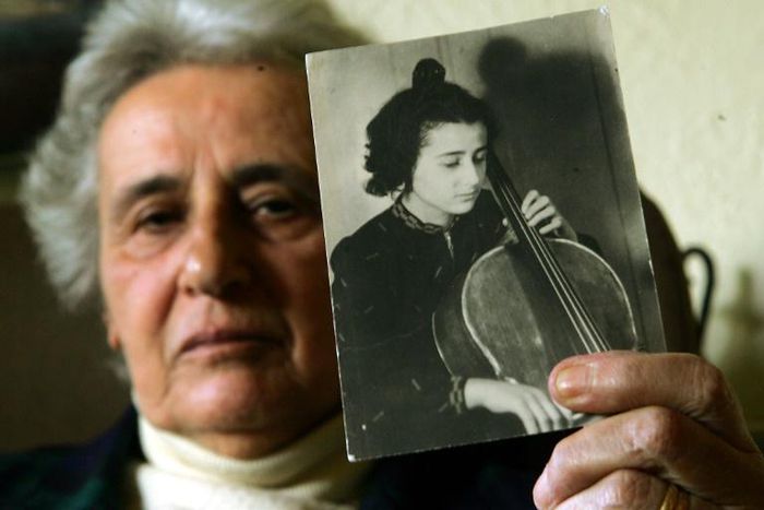 Holocaust survivor Anita Lasker-Wallfisch, pictured here in 2005, holds up a portrait of herself playing the cello in Berlin before World War II